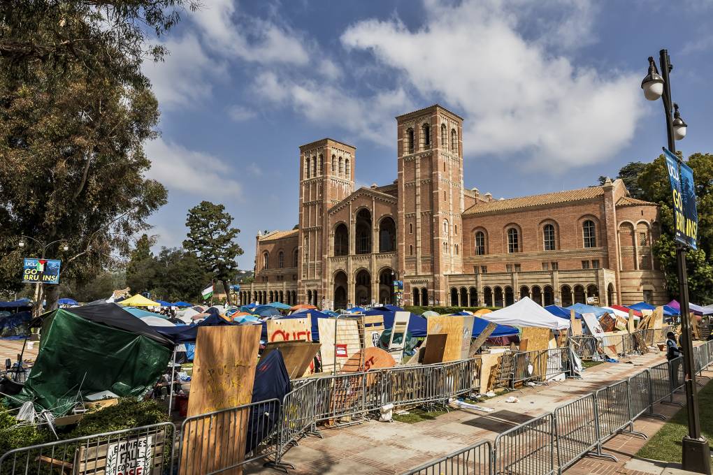 An encampment with tents and fencing on a college campus.