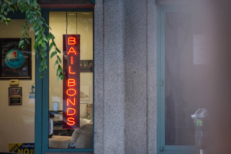 A neon red sign that reads 'Bail Bonds' inside a window.