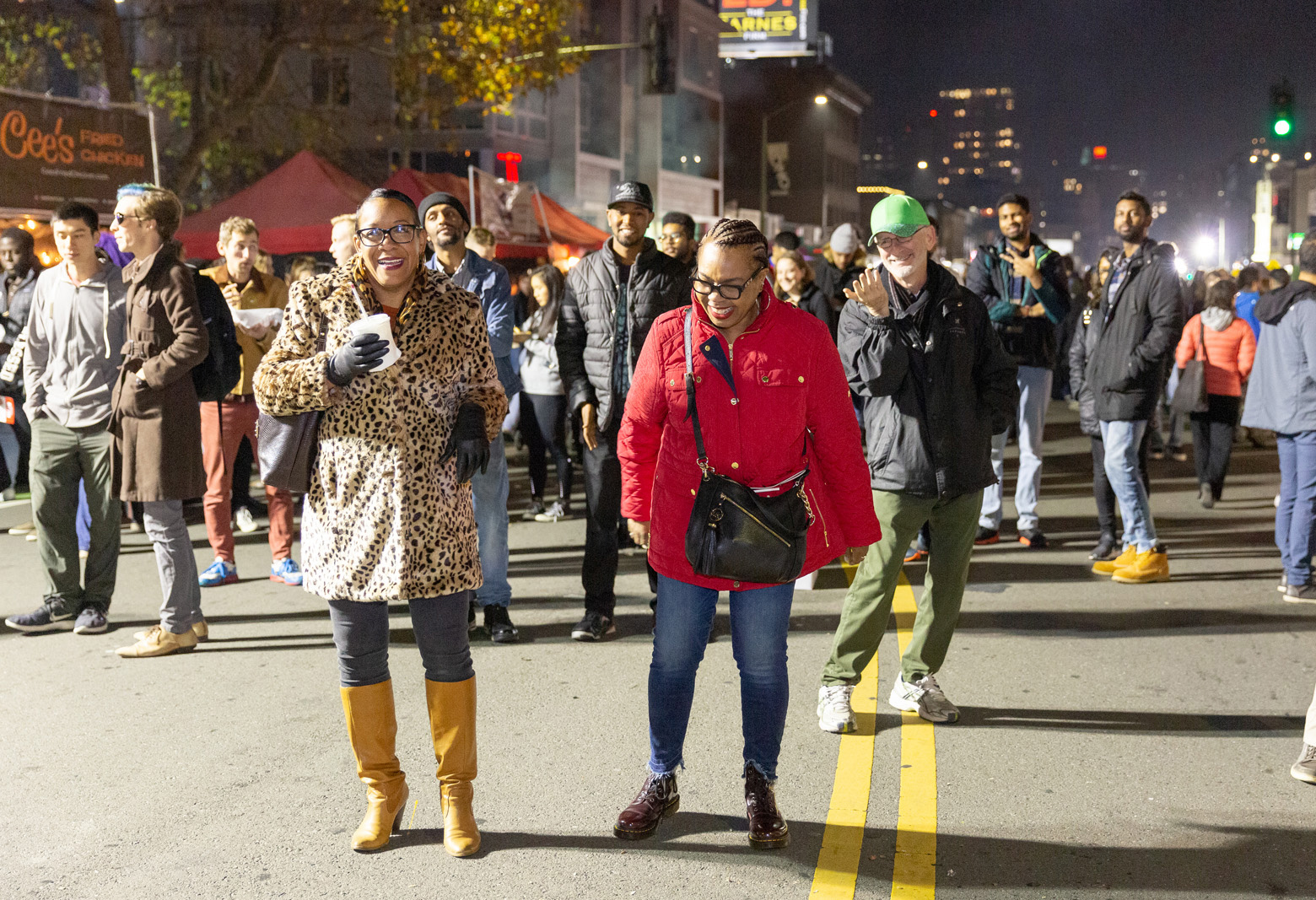 Women laugh and smile at a street fair in Oakland.