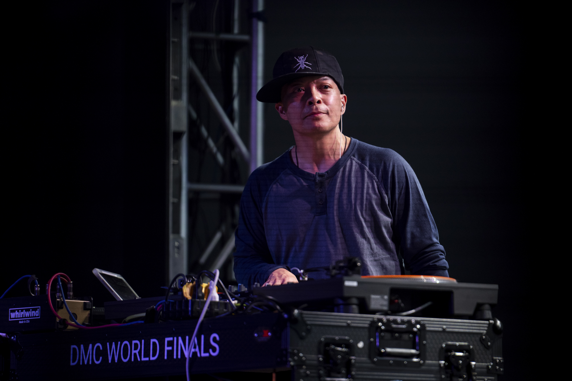 A person wearing a baseball cap stands at a table under fluorescent lighting.