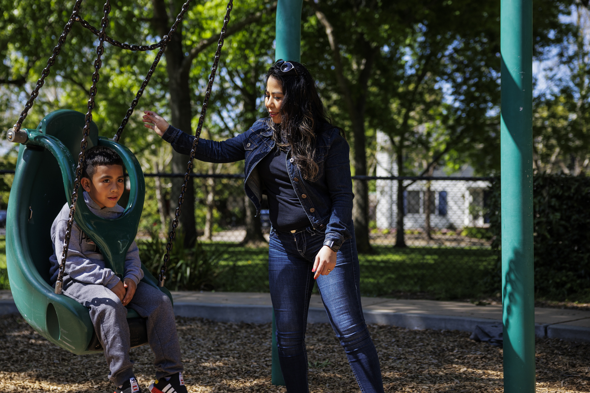 woman pushes a kid in a swing