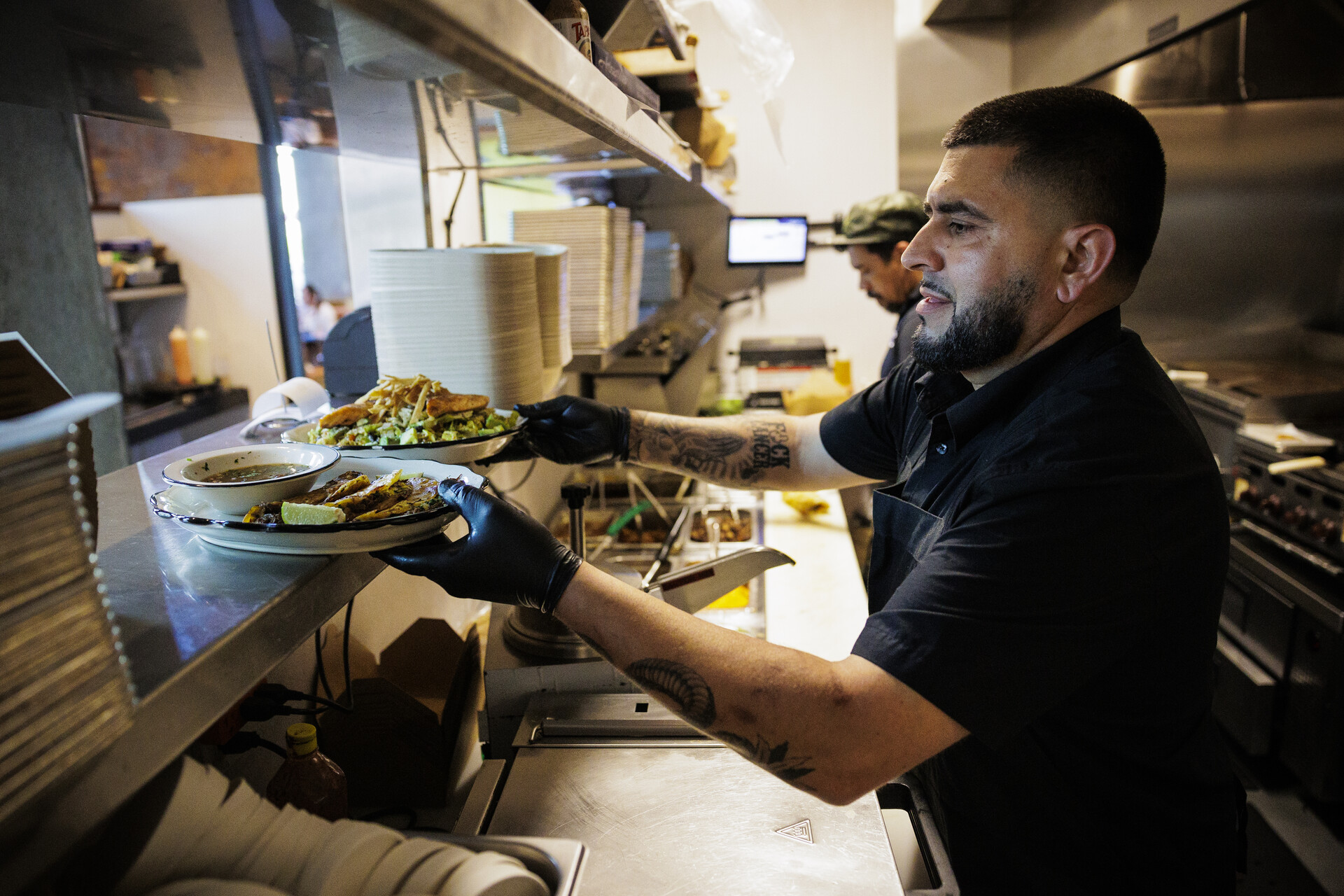 A chef puts plates of food that are ready to be served onto the pass inside a restaurant kitchen.