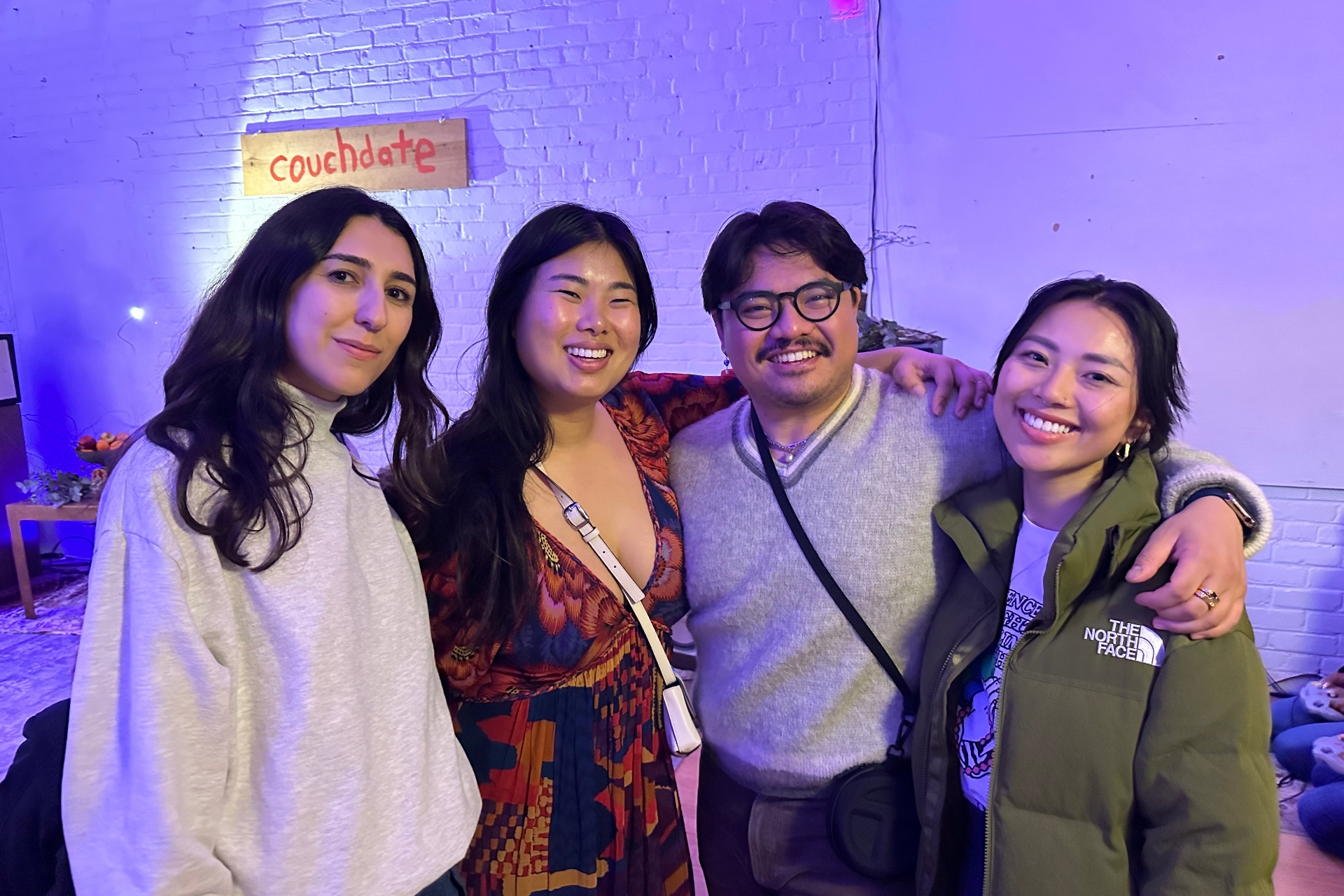 Four people pose in front of a sign that reads 'couchdate'